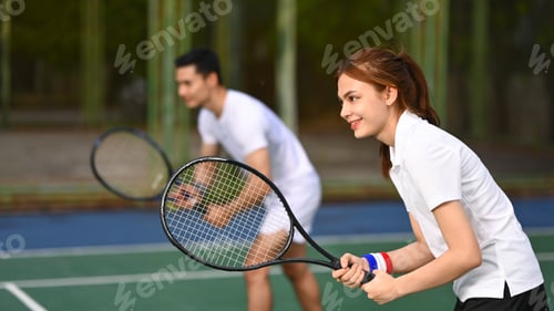 Preview: Two tennis players crouching in ready position and holding racket while waiting for serving ball.