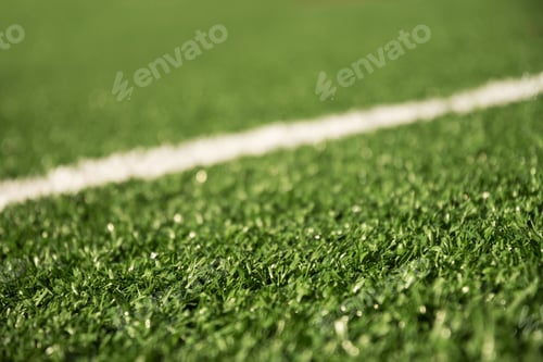Preview: Artificial green grass with white stripe of soccer field. Close up.