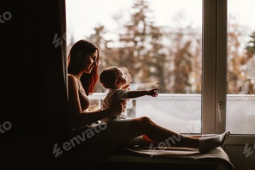 Preview: mom and baby toddler are sitting together on the windowsill, brown toning