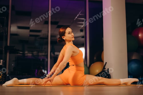 Preview: Sporty fit active sexy young tattooed woman in sportswear stretch sit legs split on floor in gym