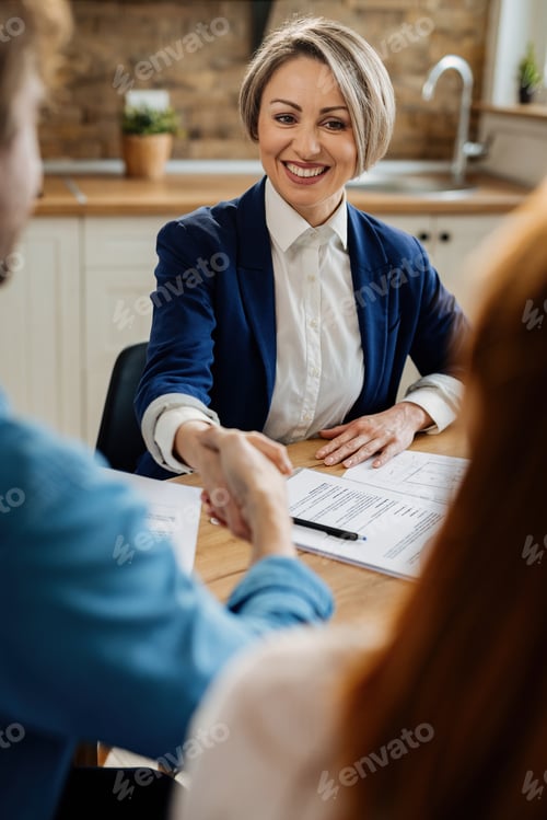 Preview: Happy real estate agent shaking hands with her clients.
