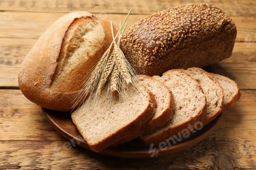 Preview: Different types of bread and wheat spikes on wooden table, closeup
