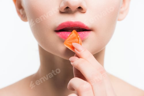 Preview: cropped view of woman holding orange jelly candy isolated on white