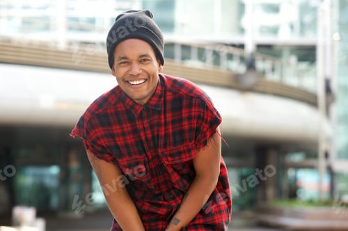Preview: trendy young african american man smiling with beanie outside in city