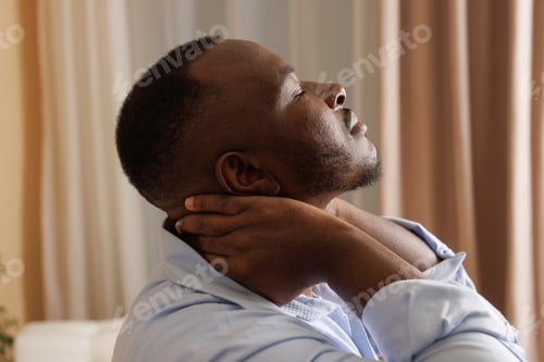 Preview: Man Suffering from Neck Pain at Home Holding Neck for Relief and Comfort After a Long Day