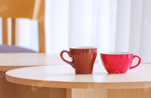 Preview: Two red and brown coffee mug on round wooden table in modern coffee shop, close up with copy space
