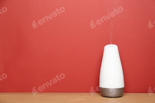 Preview: Essential oils diffuser on wooden table near red wall. Space for text
