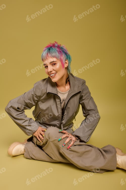 Preview: Colorful young woman poses in a studio with vibrant dyed hair and stylish outfit