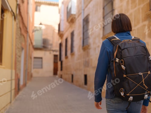 Preview: woman strolling through charming narrow streets of Denia,