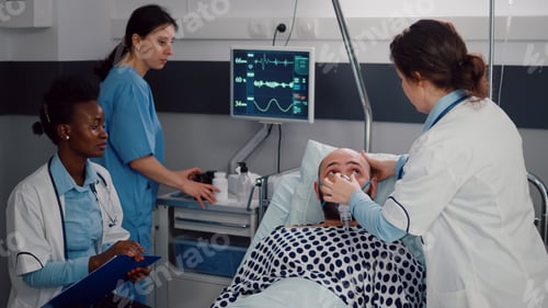 Preview: Sick man resting in bed while woman medic putting oxygen mask
