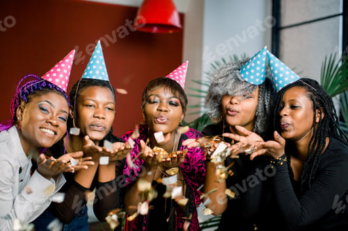 Preview: Confetti party. Happy young African group of people celebrating new year eve and blowing confetti
