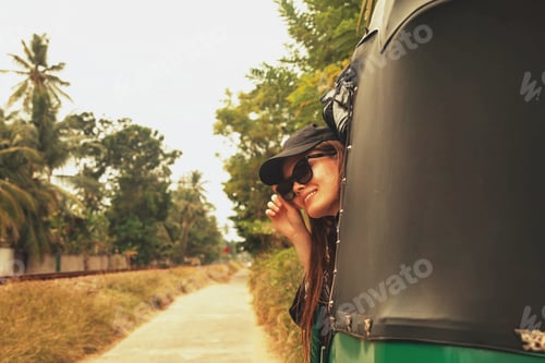 Preview: A young female tourist rides a tuk-tuk traveling in a tropical country