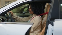 Preview: Happy African American woman sit on driver seat inside car smiling girl buyer turning steering wheel