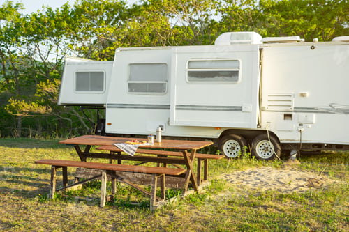 Preview: Breakfast on a wooden table on the background of a travel trailer.