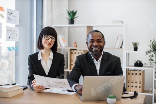 Preview: Colleagues posing at writing desk with laptop and documents