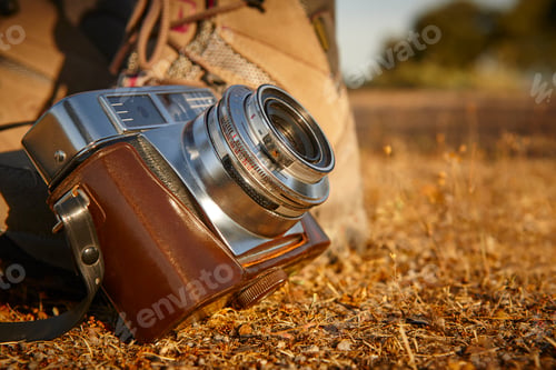 Preview: Vintage camera with hiking boots on the ground. Travel background