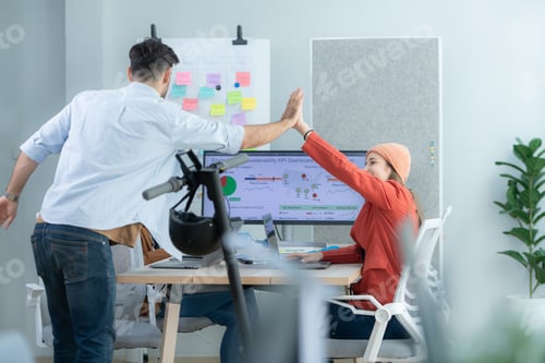 Preview: Young designer woman giving high five to her colleague at modern startup office