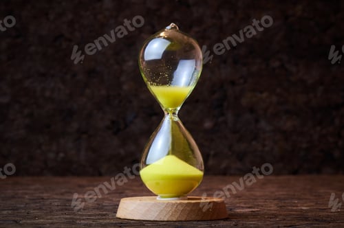 Preview: Sand running through the bulbs of an hourglass on a dark cork tree background.