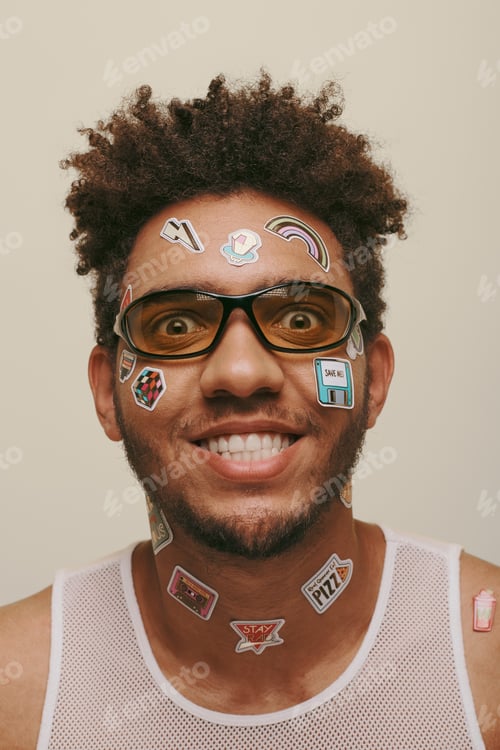Preview: cheerful african american man in sunglasses with trendy stickers on face on grey background