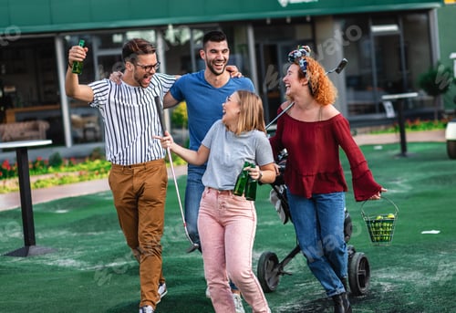 Preview: Group of smiling friends going to play mini golf in the city.