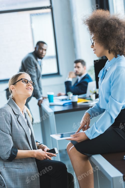 Preview: multicultural businesswomen talking and looking at each other in office