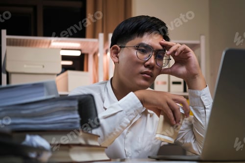 Preview: Asian young tired staff businessman using desktop computer having overwork project overnight