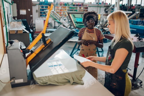 Preview: Female interracial printing shop workers working with heating press.