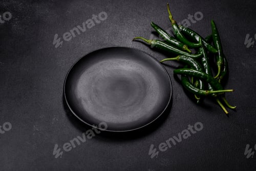 Preview: Hot pepper of green color on a dark concrete background