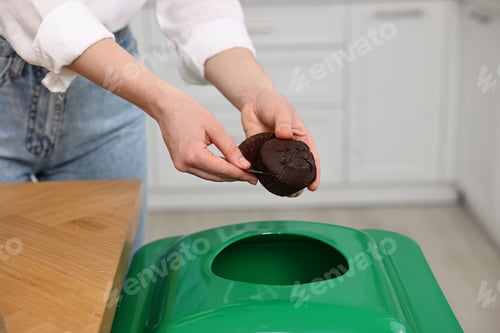 Preview: Garbage sorting. Woman throwing muffin liner into trash bin indoors, closeup