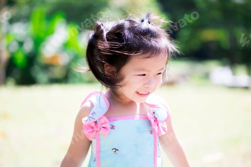 Preview: Happy cute girl wearing mint green shirt, smile sweet. Children walk in the garden on green lawn.
