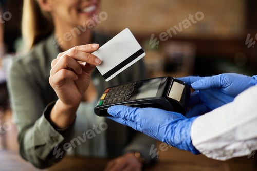 Preview: Close-up of female customer making contactless payment in a cafe.