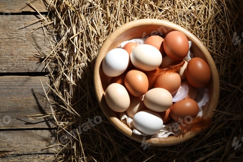 Preview: Raw chicken eggs, feathers and straw on wooden table, top view. Space for text