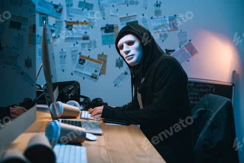 hacker enmascarado desarrollando malware en su lugar de trabajo