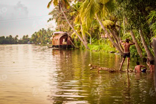 Preview: Shallow focus of people on the river surrounded by tropical trees and houseboats as a background