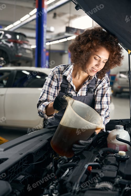 Preview: Smiling young auto repairman pouring oil into a generator
