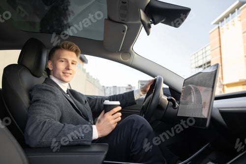 Preview: Handsome Caucasian man sitting in modern self-steering electric vehicle, and having a break with