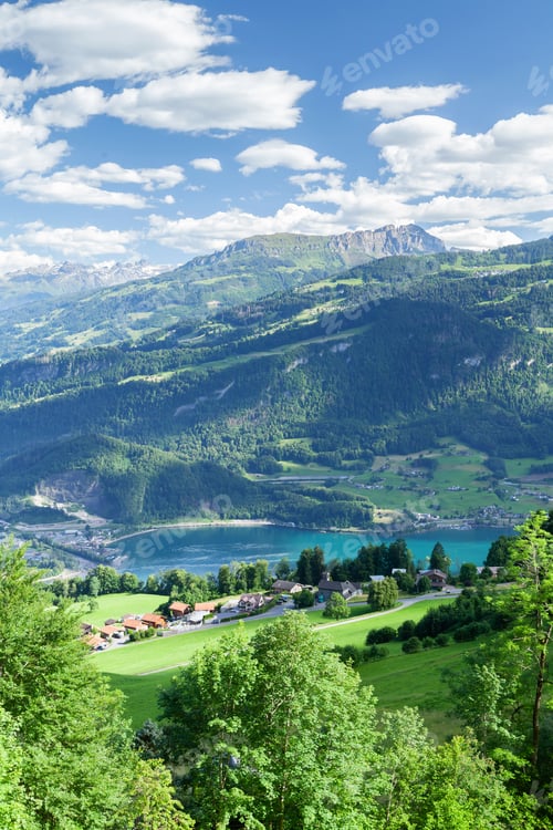 Preview: Panoramic view of lake, countryside, green alpine meadows and mountains