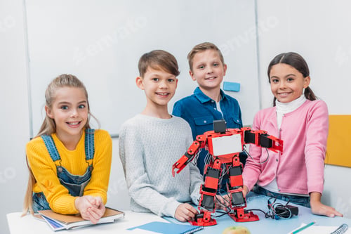 Preview: happy schoolchildren standing at desk with red electric robot in stem class