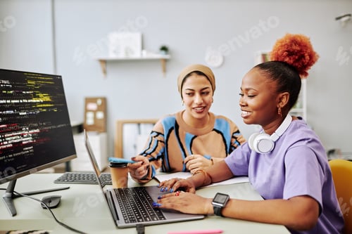 Preview: Two young women working on software development project together and smiling