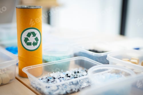 Preview: A can with a green recycle logo sits on a table next to a container of beads. The container is fille