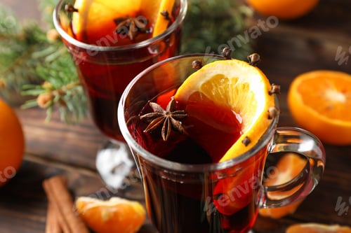 Preview: Glasses of tasty mulled wine with orange on wooden background, close up
