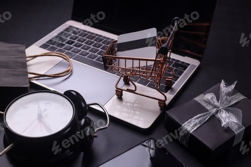 Preview: Black monochromatic composition of laptop, shopping cart, alarm clock, gift box and smartphone.