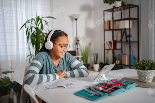 Preview: Young girl learning online with headphones and tablet