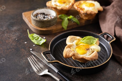 Preview: Breakfast idea. Scrambled eggs in puff pastry with cheese and bacon on a stone plate. Copy space.