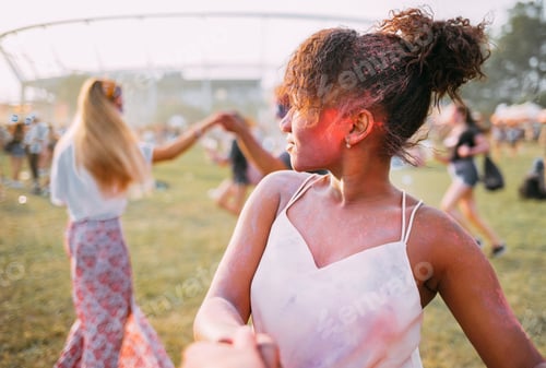Preview: African American young woman with friends dancing at summer holi festival