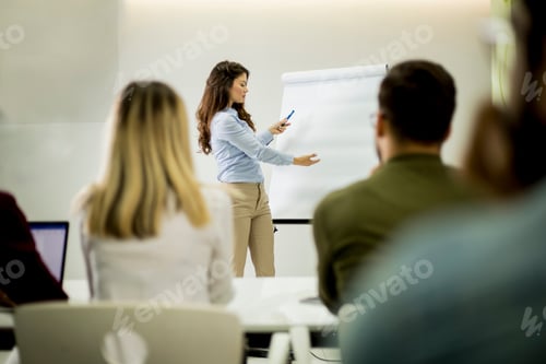 Preview: Creative positive female leader talking about business plan with students during workshop