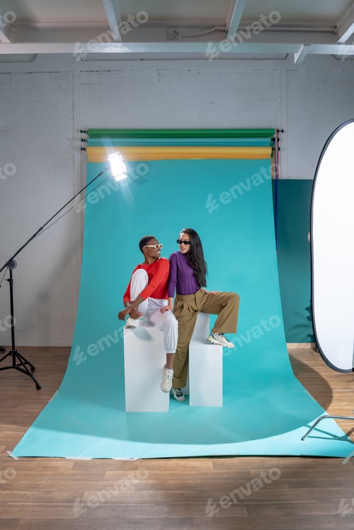 Preview: Two women pose on a color background cyclorama in a studio photo shoot.