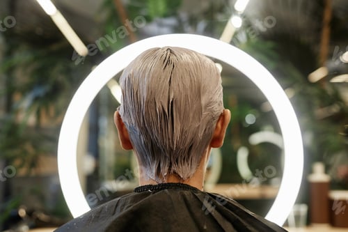 Preview: Back View of Man with Bleached Hair Facing Ring Light in Beauty Salon