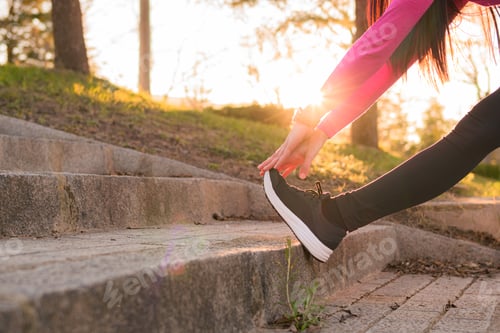 Preview: Sportswoman stretching in a park at sunset