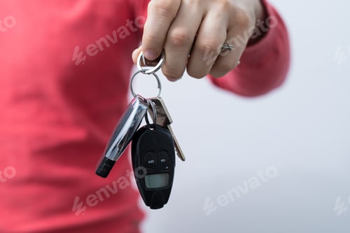 Preview: Closeup shot of a person holding car keys under the lights on a blurry background